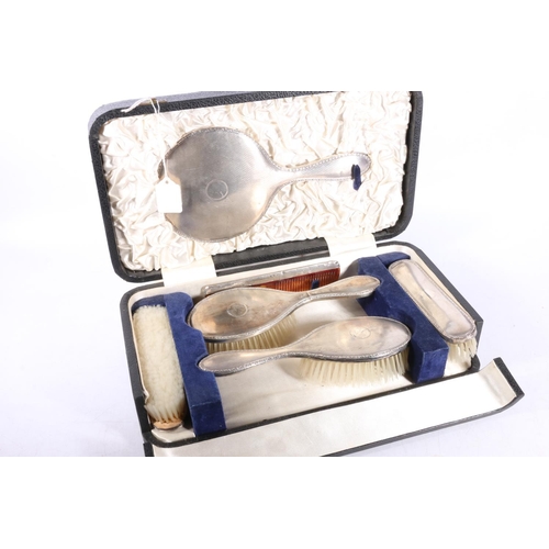 597 - George V silver dressing table set of mirror, four brushes and comb, in fitted case, Birmingham 1938