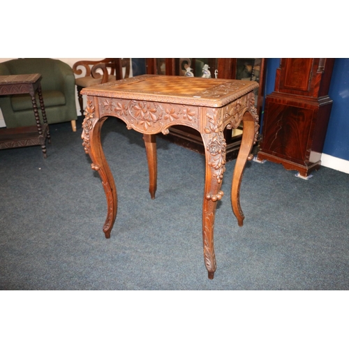 669 - Early 20th century games table with undertier drawers and shelves, heavily carved with foliage, 76cm... 