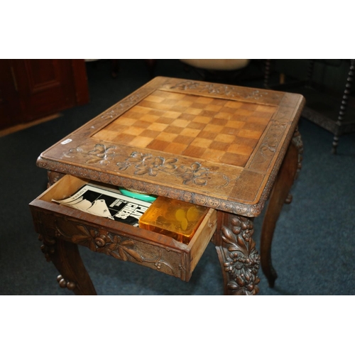 669 - Early 20th century games table with undertier drawers and shelves, heavily carved with foliage, 76cm... 