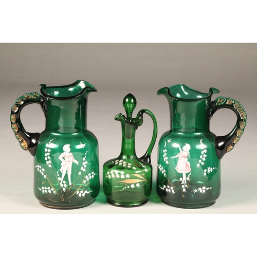 197 - Trio of Mary Gregory painted emerald green glassware, consisting of two jugs and a decanter, height ... 