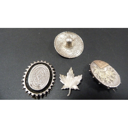 228 - Four silver brooches to include a brooch in the form of a Mexican sombrero, and Canadian maple leaf ... 