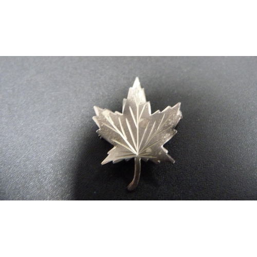 228 - Four silver brooches to include a brooch in the form of a Mexican sombrero, and Canadian maple leaf ... 