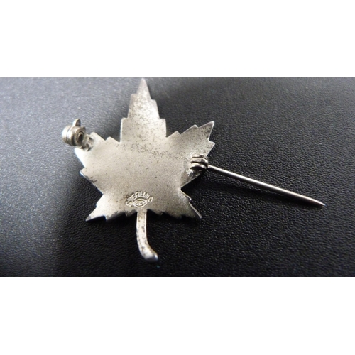 228 - Four silver brooches to include a brooch in the form of a Mexican sombrero, and Canadian maple leaf ... 