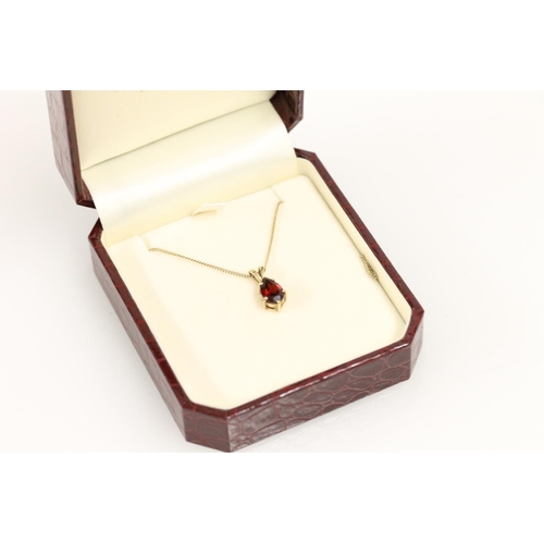 509 - 9ct gold and pear cut red stone pendant on gold chain, 2.6g