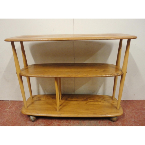 448 - Ercol blonde elm console bookcase with three tiers, on turned uprights and castors, label to the und... 