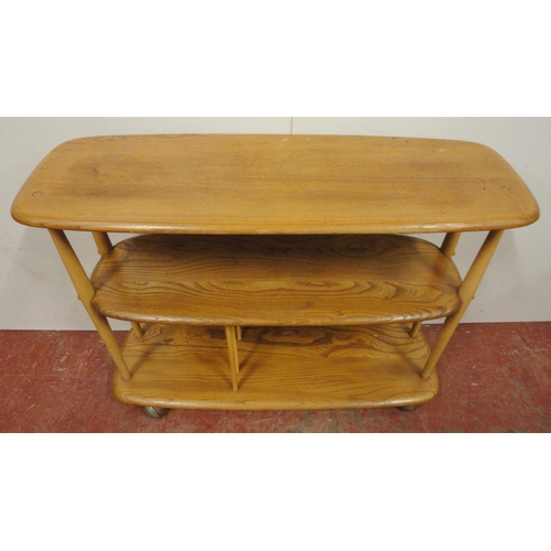 448 - Ercol blonde elm console bookcase with three tiers, on turned uprights and castors, label to the und... 