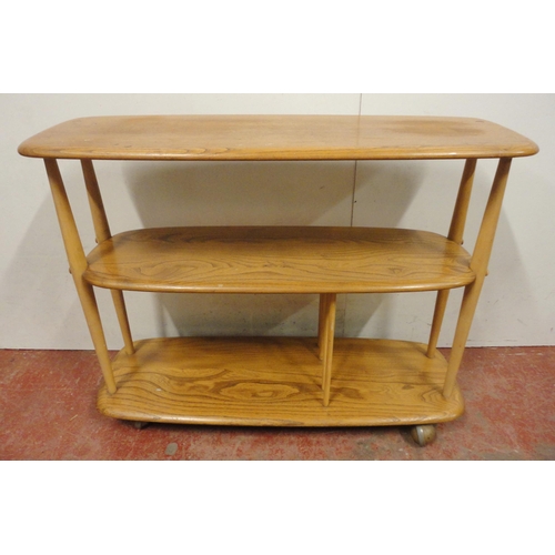 448 - Ercol blonde elm console bookcase with three tiers, on turned uprights and castors, label to the und... 