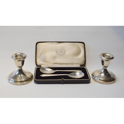 78 - Pair of silver dwarf candlesticks, loaded, and a pair of silver spoons, cased.