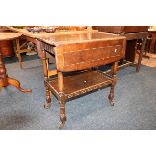 640 - 1920s oak tea trolley with drop leaves, under tier gallery, raised on castors, 75cm high.