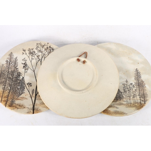 78 - Three Studio Pottery wall plates sgraffito decorated with forest scenes, 27cm diameter.