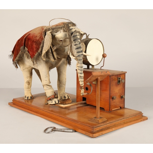 270 - An automaton figure of an elephant mounted on a wooden base, peering at the music on a stand through... 