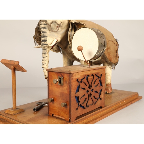 270 - An automaton figure of an elephant mounted on a wooden base, peering at the music on a stand through... 