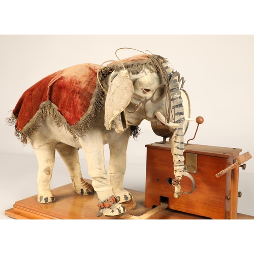 270 - An automaton figure of an elephant mounted on a wooden base, peering at the music on a stand through... 