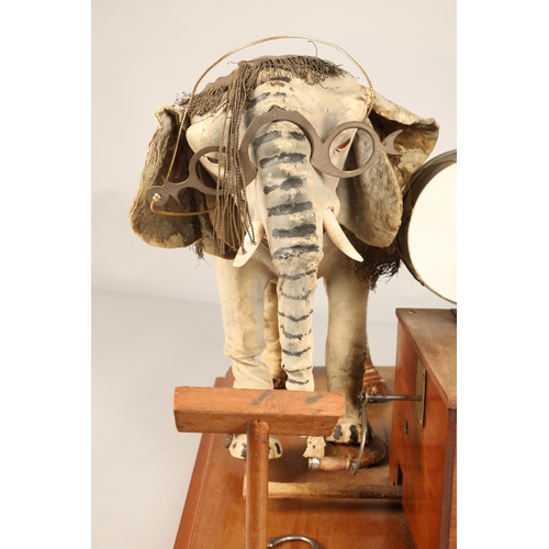 270 - An automaton figure of an elephant mounted on a wooden base, peering at the music on a stand through... 