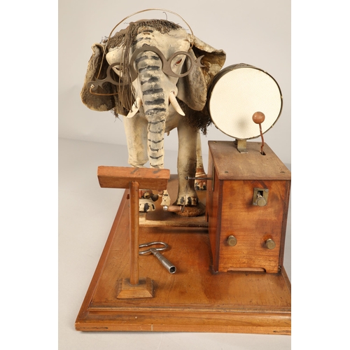 270 - An automaton figure of an elephant mounted on a wooden base, peering at the music on a stand through... 