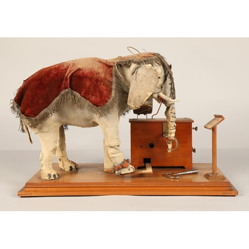 270 - An automaton figure of an elephant mounted on a wooden base, peering at the music on a stand through... 