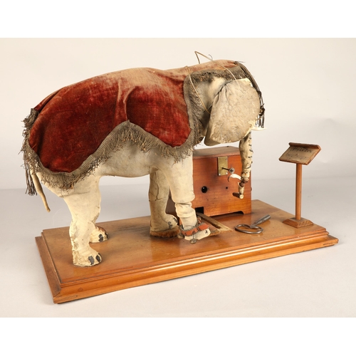 270 - An automaton figure of an elephant mounted on a wooden base, peering at the music on a stand through... 