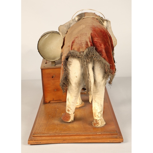 270 - An automaton figure of an elephant mounted on a wooden base, peering at the music on a stand through... 