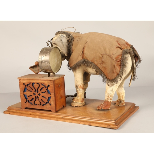 270 - An automaton figure of an elephant mounted on a wooden base, peering at the music on a stand through... 