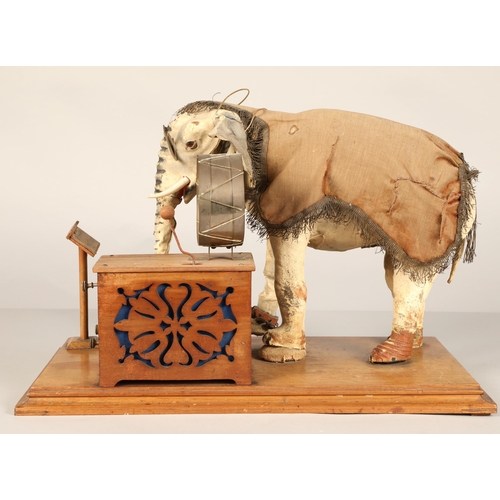 270 - An automaton figure of an elephant mounted on a wooden base, peering at the music on a stand through... 