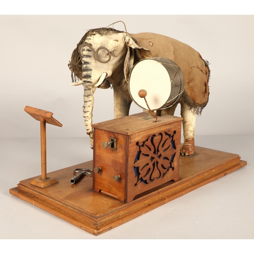 270 - An automaton figure of an elephant mounted on a wooden base, peering at the music on a stand through... 