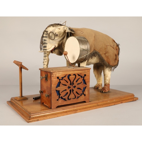 270 - An automaton figure of an elephant mounted on a wooden base, peering at the music on a stand through... 