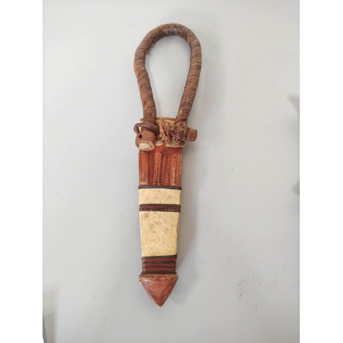 346 - A Sudanese arm knife with tapering straight blade and carved wooden hilt. Contained in tooled leathe... 