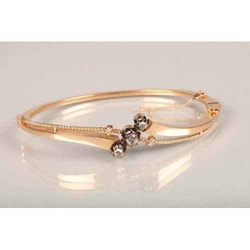 142 - Yellow metal and three stone diamond bangle, the hinged bangle with twisted wirework frame set with ... 