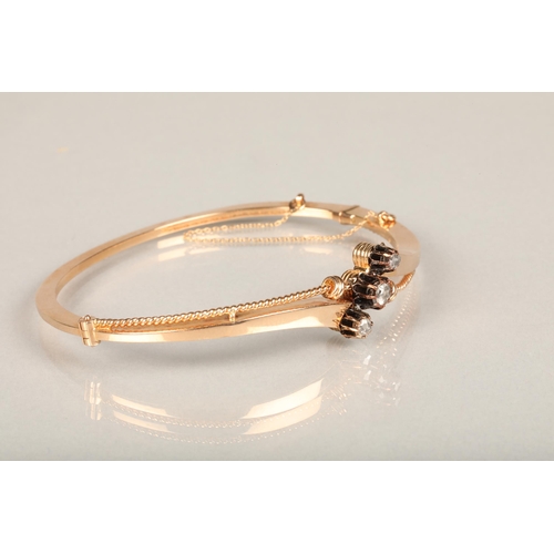 142 - Yellow metal and three stone diamond bangle, the hinged bangle with twisted wirework frame set with ... 