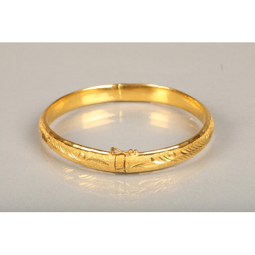 147 - Chinese yellow gold bangle, the textured surface engraved with floral designs, internal W5.7cm, 21g,... 