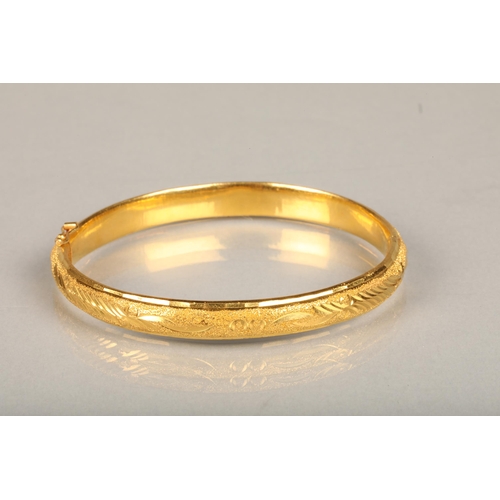 147 - Chinese yellow gold bangle, the textured surface engraved with floral designs, internal W5.7cm, 21g,... 