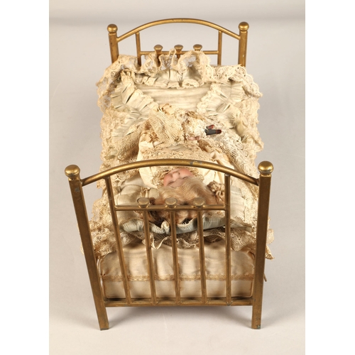 269 - A 19th century musical automaton in the form of a Victorian doll lying in a brass bedstead and holdi... 