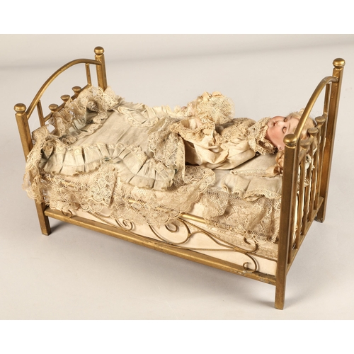 269 - A 19th century musical automaton in the form of a Victorian doll lying in a brass bedstead and holdi... 