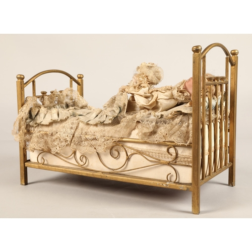 269 - A 19th century musical automaton in the form of a Victorian doll lying in a brass bedstead and holdi... 