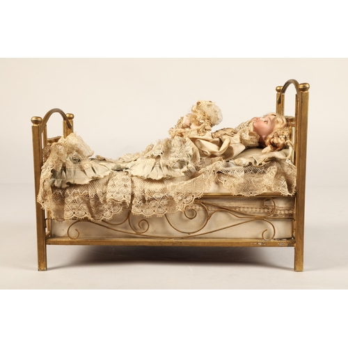 269 - A 19th century musical automaton in the form of a Victorian doll lying in a brass bedstead and holdi... 