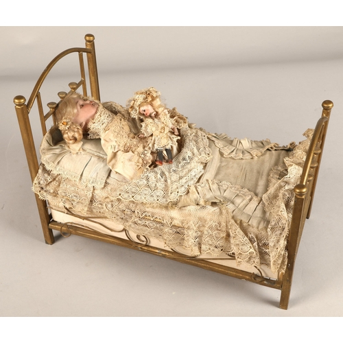 269 - A 19th century musical automaton in the form of a Victorian doll lying in a brass bedstead and holdi... 