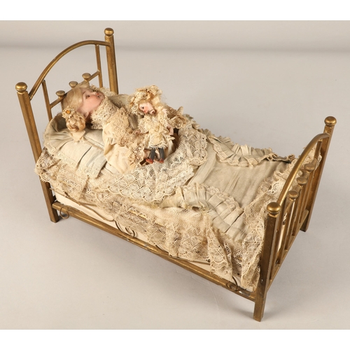 269 - A 19th century musical automaton in the form of a Victorian doll lying in a brass bedstead and holdi... 