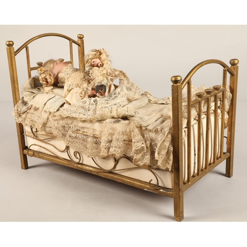 269 - A 19th century musical automaton in the form of a Victorian doll lying in a brass bedstead and holdi... 