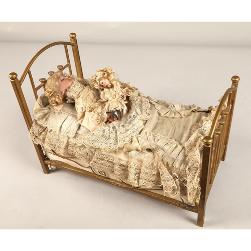 269 - A 19th century musical automaton in the form of a Victorian doll lying in a brass bedstead and holdi... 