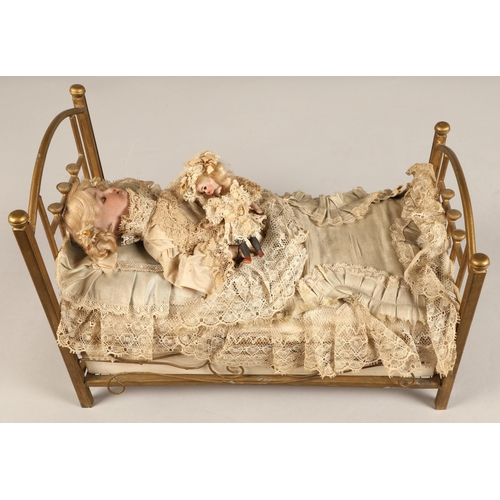 269 - A 19th century musical automaton in the form of a Victorian doll lying in a brass bedstead and holdi... 