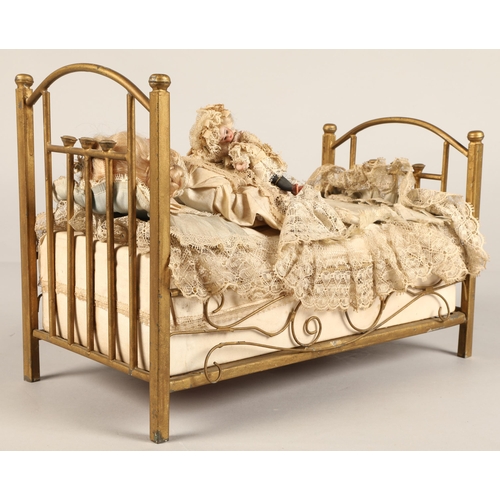 269 - A 19th century musical automaton in the form of a Victorian doll lying in a brass bedstead and holdi... 