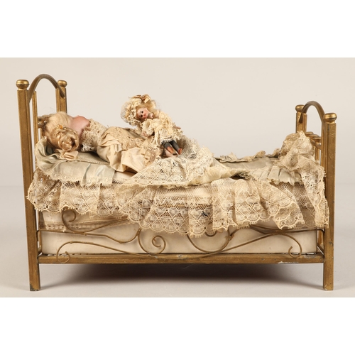 269 - A 19th century musical automaton in the form of a Victorian doll lying in a brass bedstead and holdi... 