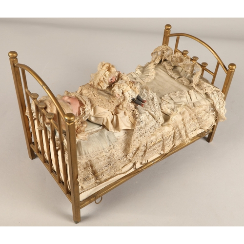 269 - A 19th century musical automaton in the form of a Victorian doll lying in a brass bedstead and holdi... 