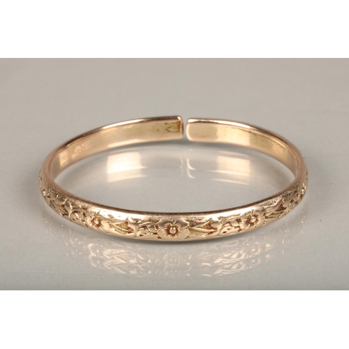 178 - Rose gold coloured yellow metal West Indian bayras bangle with floral pattern, unhallmaked but typic... 