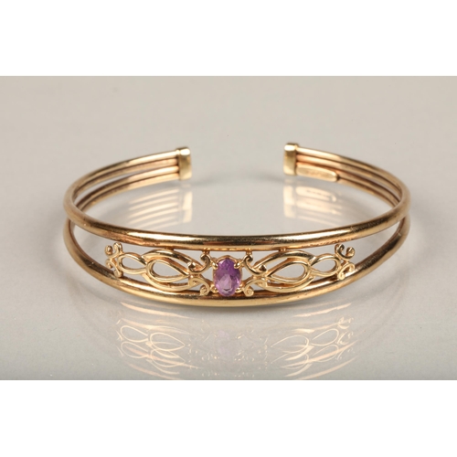 240 - 9ct gold bangle, set with an oval cut amethyst on a scrolled open work mount between a split band, i... 