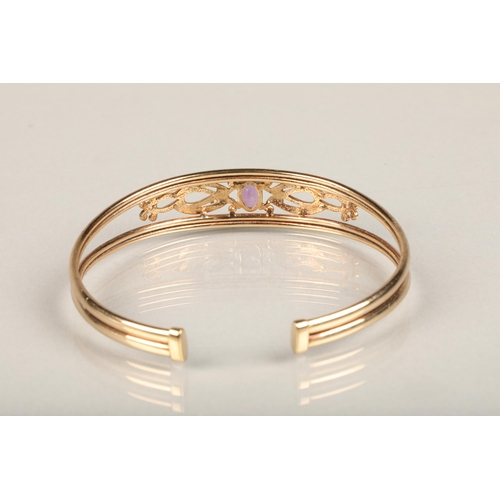 240 - 9ct gold bangle, set with an oval cut amethyst on a scrolled open work mount between a split band, i... 