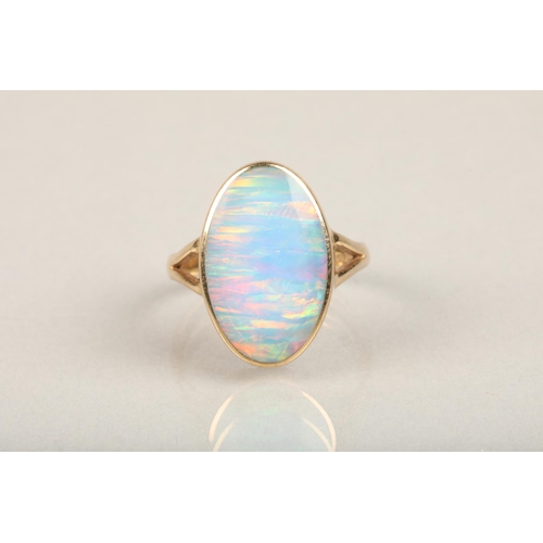 247 - 9ct gold and opal ring, the oval opal bezel set in gold frame leading to split shoulders on a plain ... 