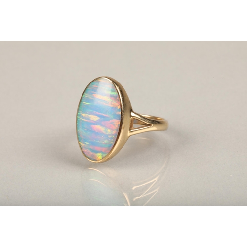 247 - 9ct gold and opal ring, the oval opal bezel set in gold frame leading to split shoulders on a plain ... 