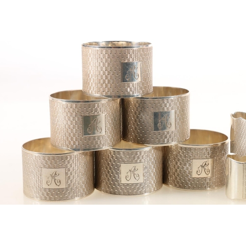 48 - Set of ten George V silver napkin rings, the round bodies with engine-turned decoration and square c... 