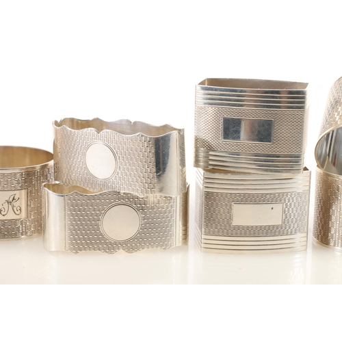 48 - Set of ten George V silver napkin rings, the round bodies with engine-turned decoration and square c... 